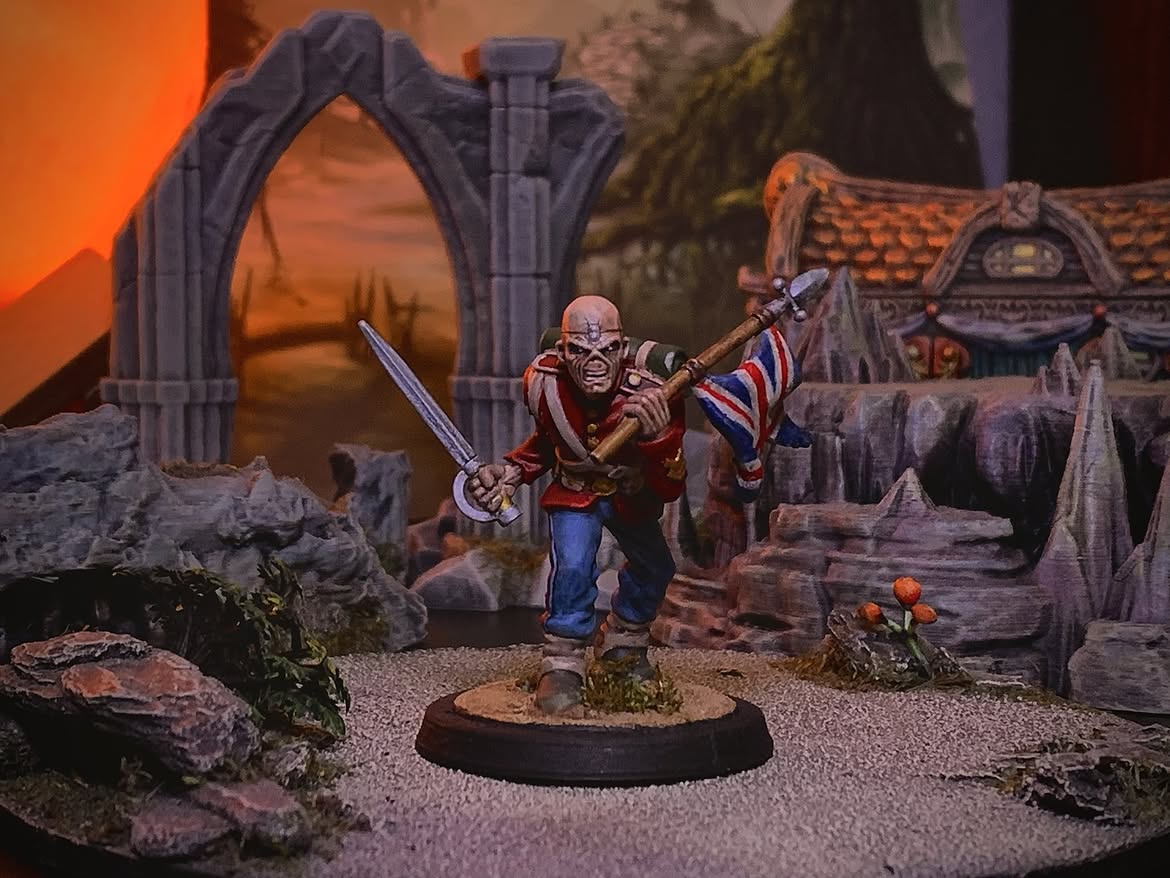 Miniatura de Eddie do Iron Maiden fantasiado de soldado britânico, empurrando bandeira do Reino Unido